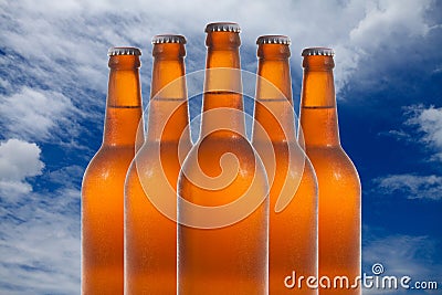 A group of five beer bottles in a diamond formation on sky backg