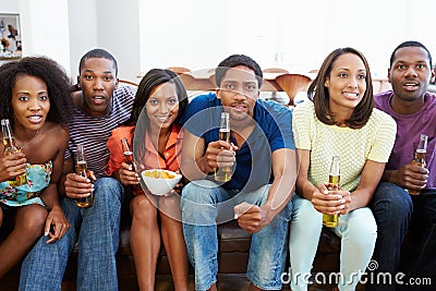 Group Of Friends Sitting On Sofa Watching TV Together