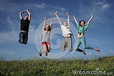 Group of jumping people on grean meadow