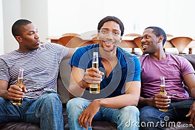 Group Of Men Sitting On Sofa Watching TV Together