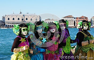 Group of people in colorful costumes and masks, view on the Grand Canal