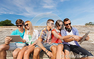 Group of smiling friends with tablet pc outdoors