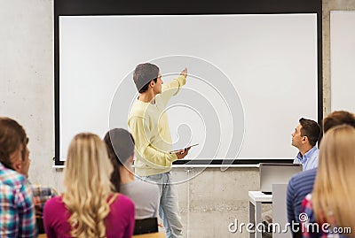 Group of smiling students and teacher in classroom