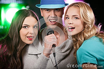 Group of three friends singing with microphone.
