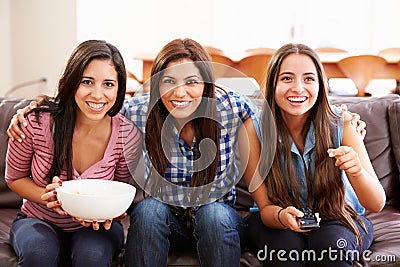 Group Of Women Sitting On Sofa Watching Sport Together