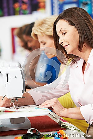 Group Of Women Using Electric Sewing Machines In class