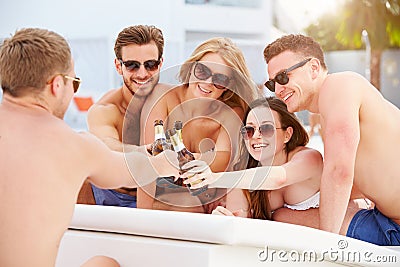 Group Of Young People On Holiday Relaxing By Swimming Pool