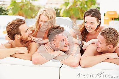 Group Of Young People On Holiday Relaxing By Swimming Pool