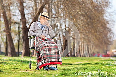 Grumpy old man sitting in a wheelchair in park