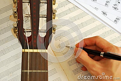 Guitar with hand composing music on manuscript