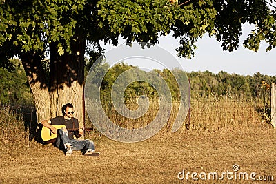 Guy Playing Guitar at Sunset under Maple Tree