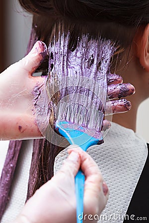 Hairdresser applying color woman in hair salon