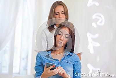 Hairdresser doing haircut for women wiht mobile phone in hairdre