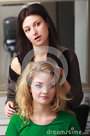 Hairstylist combing blond girl in hair salon