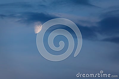 Half Moon glows in blue sky at twilight