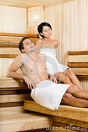 Half-naked man and young woman relaxing in sauna