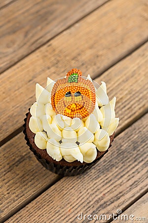 Halloween cupcake with pumpkin cake topper on an old rustic wooden table