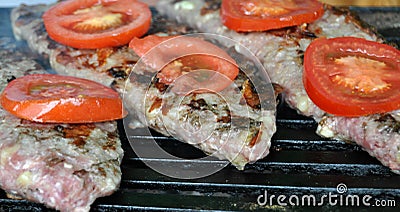 Hamburger steak and tomatoes on a grill