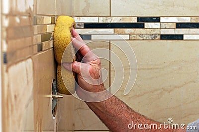 Hand applying grout to wall tiles