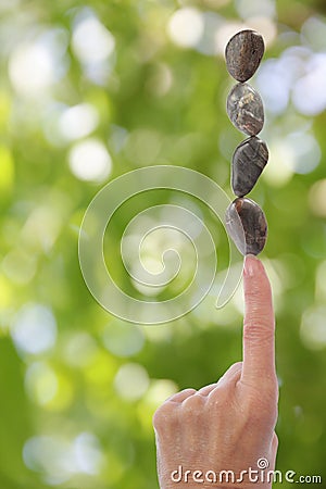Hand Balance Stones on Finger Blurred Green Bkgrnd