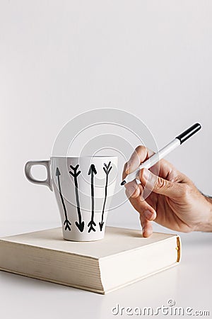 Hand drawing hipster arrows on white coffee mug.
