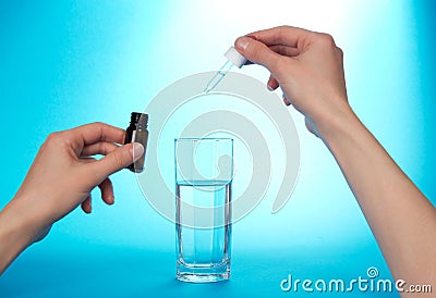The hand, dripping medical drops in glass with
