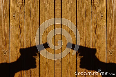 Hand with a gun on a wooden fence