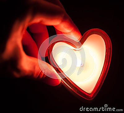 Hand holding burning candle heart