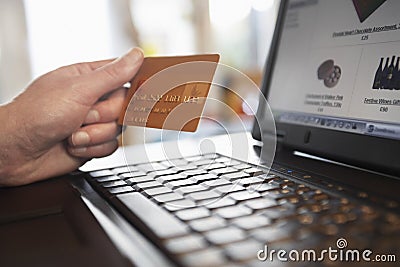 Hand Holding Credit Card In Front Of Laptop