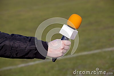 Hand holding microphone for interview during a football mach