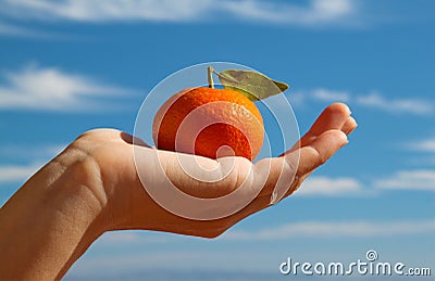 Hand holding a tangerine with leaf