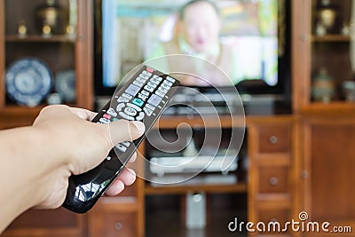 Hand holding TV remote control with television