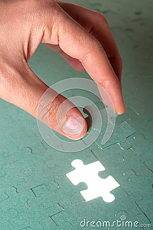 Hand inserting missing piece of jigsaw puzzle