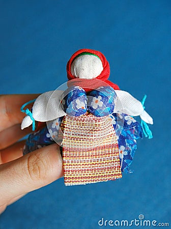 Hand-made colorful doll on blue background