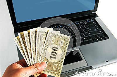 A hand with money in front of a computer