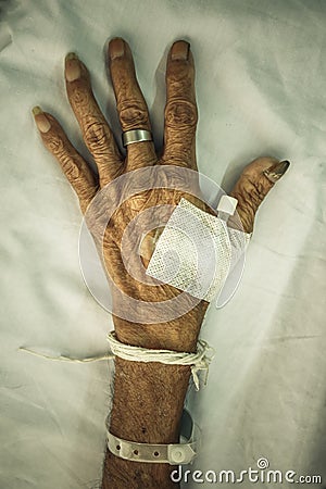 Hand of old patient with plug on bed in hospital