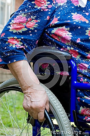 Hand of the old woman on an invalid armchair