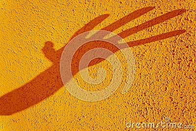 Hand shadow distorted on texturized yellow wall