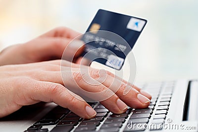 Hand typing on laptop with credit card.