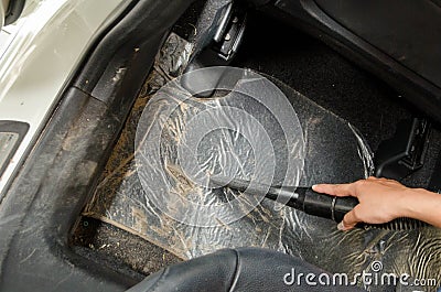 Hand vacuum cleaning dirt on a car carpet