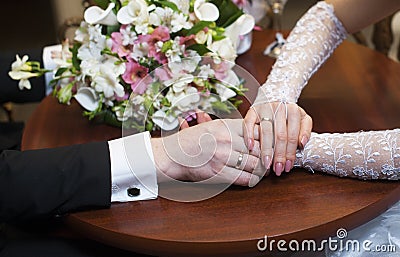 Hands of the bride and groom and wedding flowers