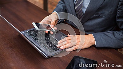 Hands of businessman with laptop and mobile phone.