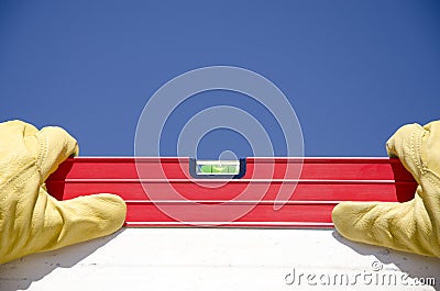 Hands with gloves on spirit level outdoor construction