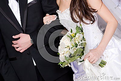 Hands of a groom and a bride with a flower bouquet