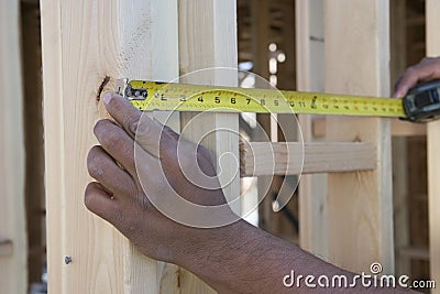 Hands Measuring Between Boards With Tape Measure At Site