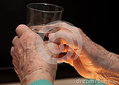 Hands of old woman and glass of water