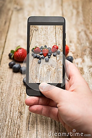 Hands taking photo of fruits on wooden.