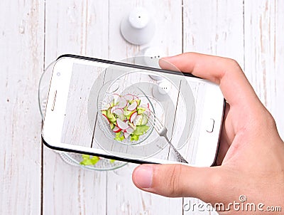 Hands taking photo radish salad with smartphone
