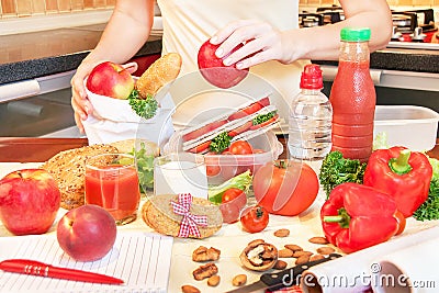 Hands of a young woman preparing school lunch box.