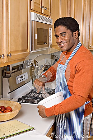 Handsome African-American man cooks in kitchen